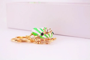 Detail of frog keychain featuring green stripes, gold crown, and inlaid crystal rhinestones