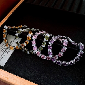 Detailed macro view of multi-colored emerald-cut zircon bracelets on a black velvet tray