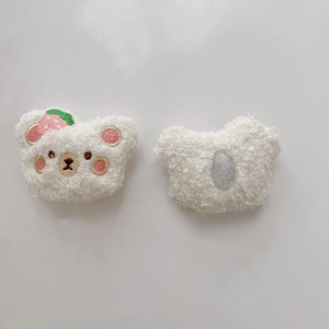 Close-up of plush bear head accessory with strawberry embroidery and fleece texture