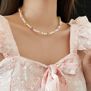 Elegant pearl and colorful stone necklace worn by a model in a floral pink dress