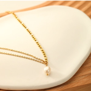 Detail of 18K gold double layer chain necklace featuring a white freshwater pearl pendant