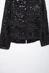 Detailaufnahme der schwarzen Tweedjacke mit Pailletten, Saumdetails und Futter auf Weiß