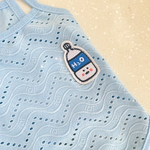 Detail of light blue hollow wave texture fabric with H2O water bottle embroidery patch