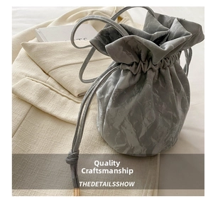 Detailed close-up of grey drawstring bucket bag featuring unique marble texture and pleated design