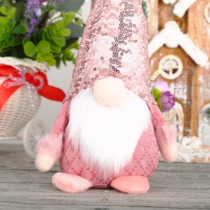 Pink sequin Christmas gnome plush toy on a rustic wooden table with festive decoration