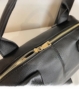 Detailed macro view of black lychee grain leather texture and smooth gold metal zipper