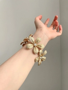 Detailed view of golden flower bracelet with brushed texture and sparkling crystal center