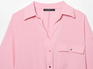 Détail du col d'une chemise rose avec logo, texture du tissu et étiquette de taille visible