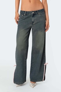 Détail du jean évasé avec laçage en ruban rose et fente latérale au bas du pantalon