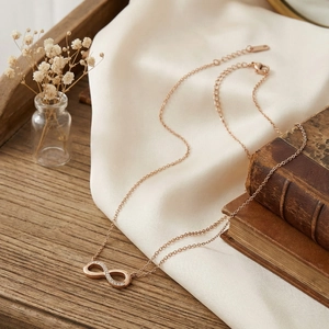 Detailed close-up of a rose gold infinity pendant necklace with sparkling inset stones