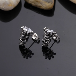Macro shot of silver skull crown stud earrings with clear zircon on black stone