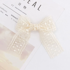 Close-up of cream lace bow accessory with delicate mesh weave on a minimal background