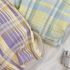 Detailed close-up of textured checkered makeup bag with smooth metal zipper and label
