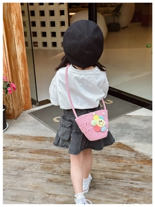 Pink woven child crossbody bag with colorful smiley flower on a young girl in white tee