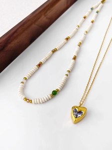 Detail of layered 18k gold necklace with purple heart pendant and colorful beads