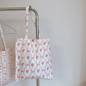 Detail of floral canvas tote bags with rose prints and striped patterns on hangers