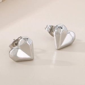 Macro detail of silver geometric heart stud earrings with 3D faceted metallic surface