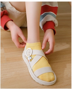 Close-up of yellow socks with cartoon goose patterns worn with white platform sandals