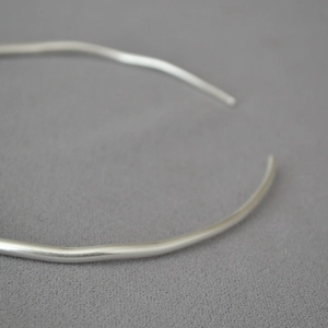 Macro shot of silver minimalist collar necklace featuring irregular wave texture details