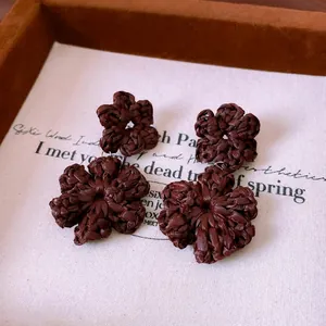 Handmade dark brown woven flower drop earrings on white card and brown velvet tray