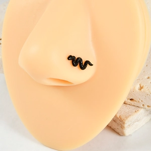 Gros plan d'un piercing de nez serpent noir en titane G23 sur un modèle en silicone