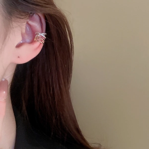 Close-up of gold layered ear cuff with crisscross zircon stones on model's ear