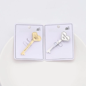 Detailed view of silver and gold heart key brooches with 'I LOVE YOU' engraving