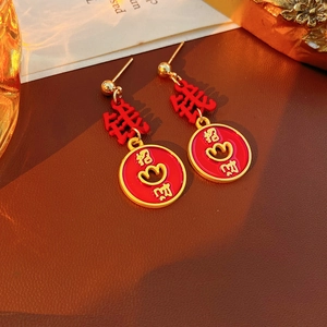 Detailed macro view of vintage red enamel earrings with golden Chinese lucky charms