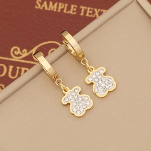 Golden bear dangle earrings with sparkling rhinestones on a textured brown background