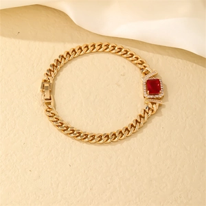 Macro detail of gold Cuban link bracelet with a large red zircon gemstone and micro-pavé diamonds