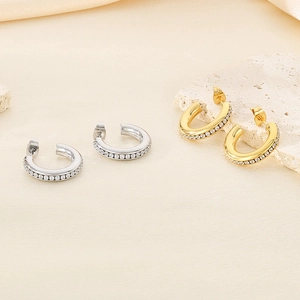 Detail of gold and silver C-shaped hoop earrings with shimmering pavé zircon setting
