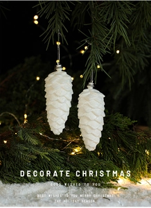 Detailed view of white glittered pinecone ornament hanging on a festive Christmas tree branch
