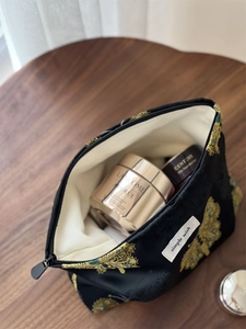 Detail of black jacquard makeup bag with gold embroidery and spacious inner lining