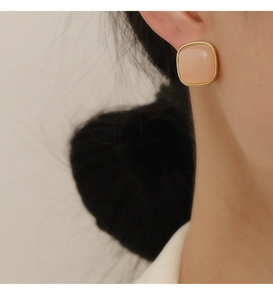 Macro view of pink square stone earring with gold frame shown on the ear lobe