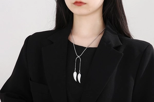 Detail of silver angel wing pendant and snake chain necklace on a female model
