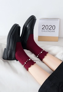 Close-up of burgundy crew socks with elegant pearl accents and ruffled trim details
