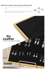 Detail of black velvet and gold metal jewelry tray showcasing various earrings and rings