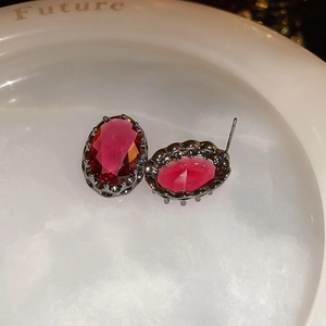 Macro shot of vintage oval ruby earrings set in gunmetal on a white ceramic dish