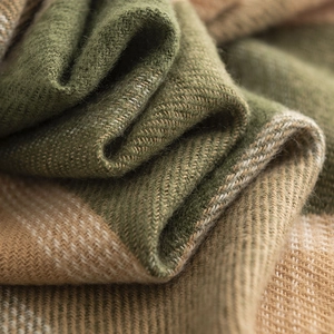Macro detail showing green and beige herringbone weave cashmere-like fabric texture