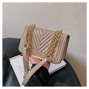 Detail of elegant apricot quilted crossbody bag with gold chain and V-pattern stitching
