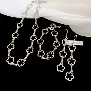 Detail of silver clover jewelry set featuring floral hollow necklace and earrings