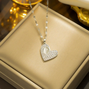 Silver heart necklace with opal inlay and hammered texture on elegant jewelry padding
