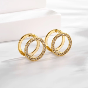 Macro detail of gold geometric hollow hoop earrings with cubic zirconia and polished finish