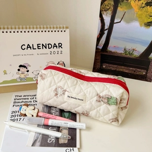 Detailed close-up of quilted cotton cosmetic bag with teddy bear prints and red zipper