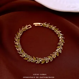Exquisite gold leaf bracelet with emerald green marquise zircons on red velvet background