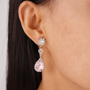 Close-up of elegant flower-shaped silver studs with pink teardrop crystal pendants