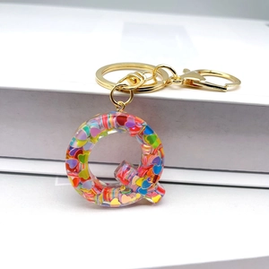 Detail of resin letter Q keychain with colorful heart sequins and gold metal ring