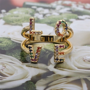 Macro shot of gold LOVE ring with multi-color micro-pave zircons and colorful stones