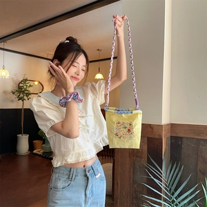 Vue détaillée du petit sac en tissu oxford jaune avec broderie florale et bandoulière violette