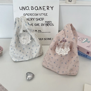 Close-up of floral canvas handbags with delicate white lace trim and single handle
